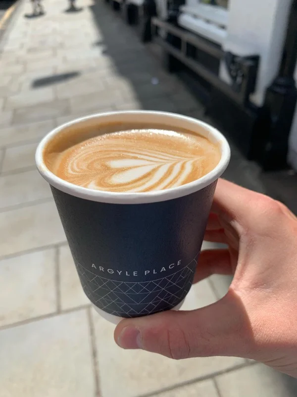 Take coffee cup with latte art street in the background 