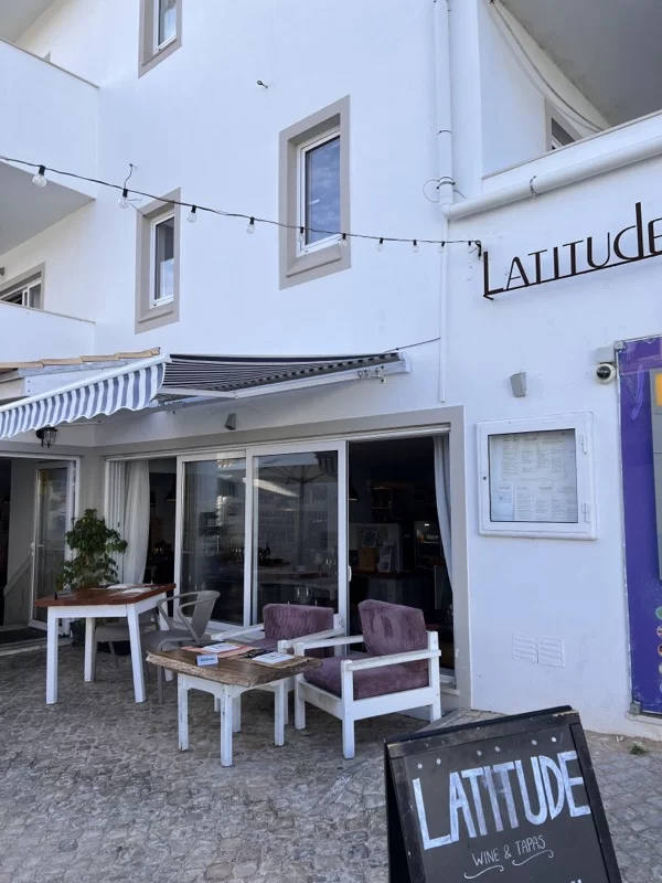 White restaurant called Latitude with tables outside