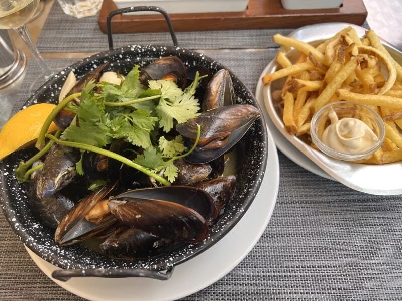 plate of mussles in black bowl and plate of hot chips in white bowl